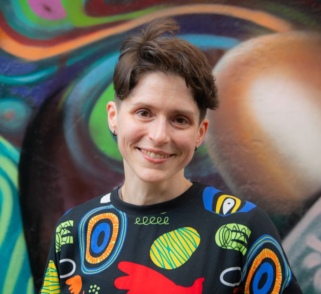 Fiona MacNeill pictured in a colourful jumper against a street art background